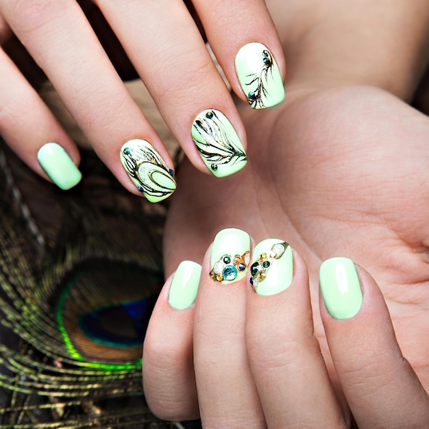 Art design manicure with peacock feather on female hands Closeup Fashion nails Photos shot in studio