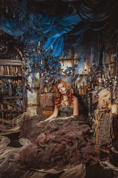 Искусство моды. Красивая молодая женщина в элегантном историческом платье и с прической в стиле барокко, сидя в студии интерьера