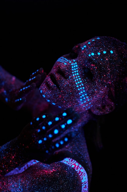 Art girl cosmos in ultraviolet light. Woman does yoga, body warm-up. Entire body is covered with colored droplets. Astral yoga. Noise, out of focus