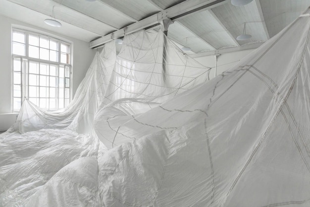 Art installation with a white parachute hanging in the huge white photo studio