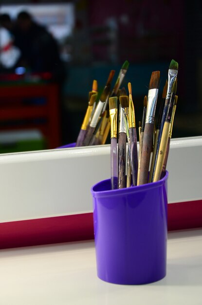 Photo art paint brushes in cup are located in the children's entertainment hall at the mirror