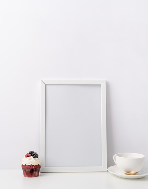 Art photo frame mockup with cup of coffee and cupcake white background