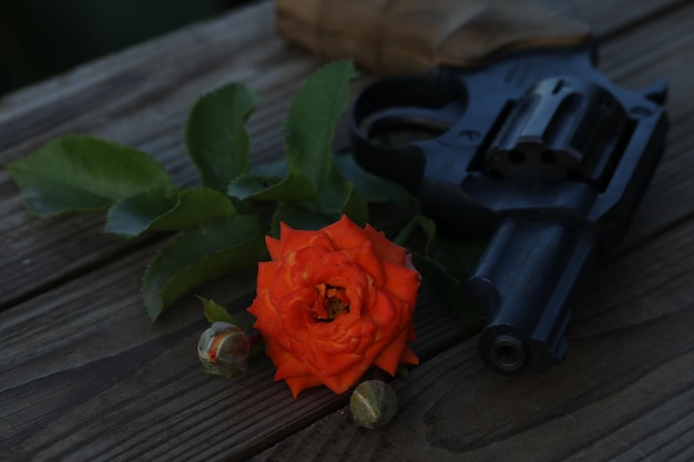 アート写真。木製の背景に銃とバラのあるヴィンテージのある静物