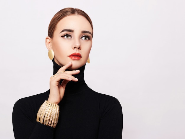 Art portrait of a beautiful, elegant woman in a black turtleneck and gold jewelry