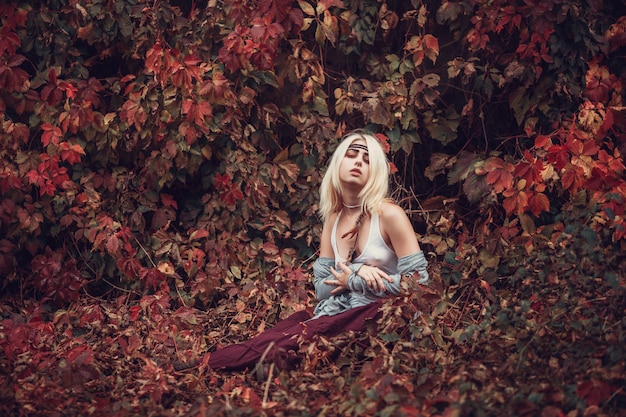 Art portrait of beautiful lonely albino girl. Pretty woman posing in park in red leaves and looking at you.