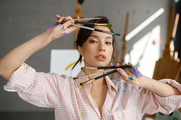 Art portrait of creative female artist showing hand with paintbrush