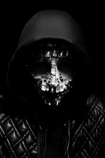 Art portrait of a hooded man with big rhinestones on his face.
mysterious mystical appearance of a man. big crystals glisten in
the dark on the guy face. blurred out of focus