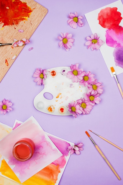 art supplies and white plastic palette with violet daisies