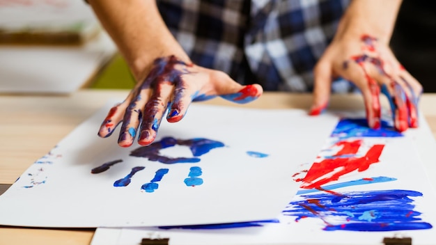 Foto scuola di classe di arteterapia stampa colorata a mano dell'uomo su carta bianca mani dell'artista imbrattate di vernice educazione hobby