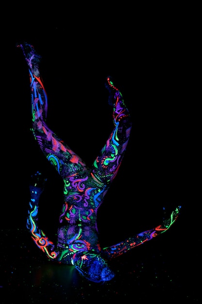 Art woman body art on body dancing in ultraviolet light. bright\
abstract drawings on girl body neon color