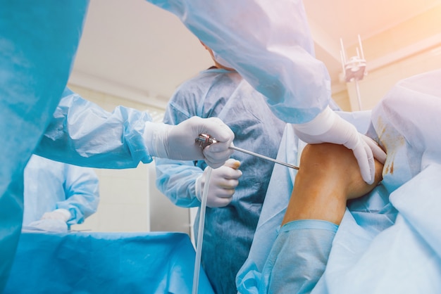 Arthroscope surgery. Orthopedic surgeons in teamwork in the operating room with modern arthroscopic tools. Knee surgery.