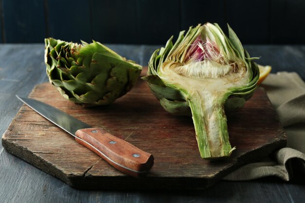 Artichokes on cutting board on color wooden background