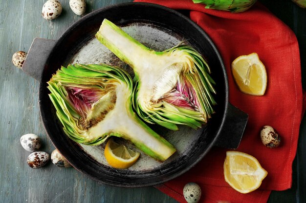 Artichokes on pan on color wooden background