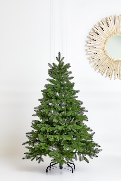 Photo artificial christmas green tree without decorations on a metal stand isolated on a white background