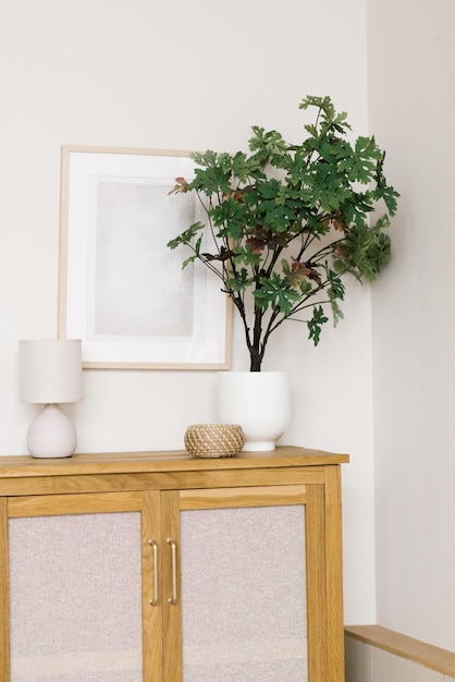 An artificial flower in a pot on a wooden chest of drawers in the living room decorative items