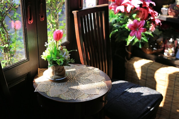 Fiori artificiali in vaso a sacco marrone sul tavolo del vecchio caffè ristorante vintage in tono scuro