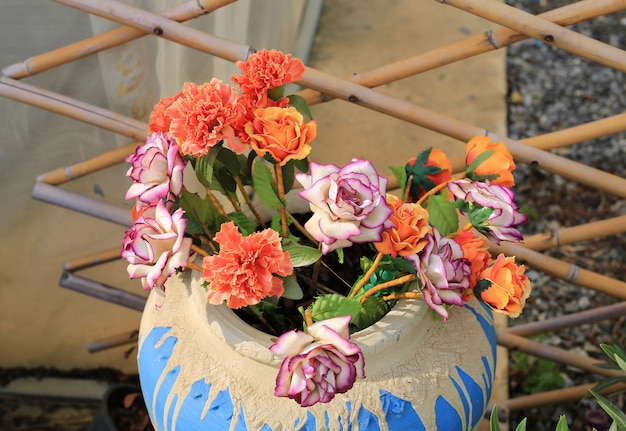 artificial flowers and leaves in ceramic jar