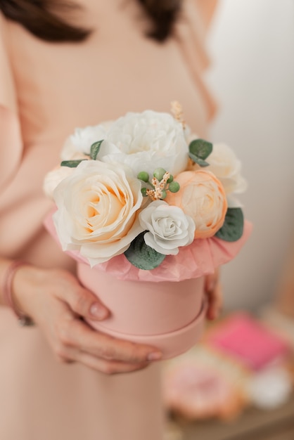 Artificial flowers in a round box. Floral element of the interior. Decorative flowers in a box.