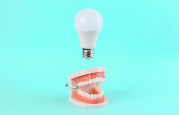 Artificial jaw with a floating light bulb on a blue background minimal idea inspiration concept art