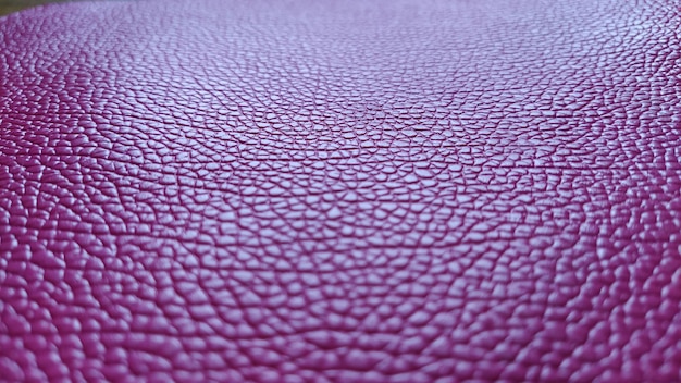 Artificial leather is bright pink or fuchsia Distinct furrows and elevations on the surface of a bag or shoe Reflection of the light Fashion accessory made of imitation pig skin Closeup