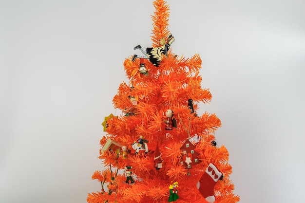 Artificial orange Christmas tree with wooden miniature decorations and ornaments hanging on branches