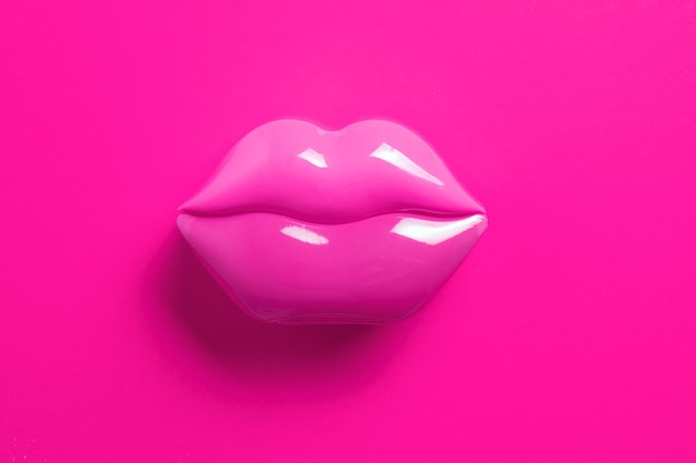 Artificial pink lips shape on pink background Flat lay Beauty care perfection concept Minimalism