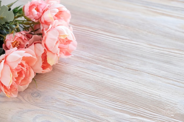 Artificial pink peonies flowers on wooden board. Copy space