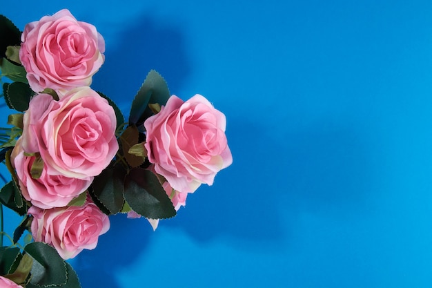 Artificial pink roses on a blue background.