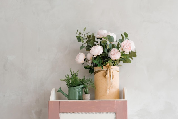 Artificial pink roses in a vase in a watering can as a decor for a children's room