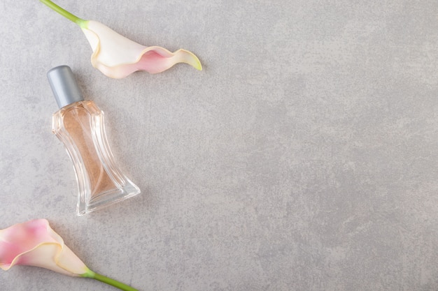 Photo artificial rose flower buds with bottle of perfume on stone.