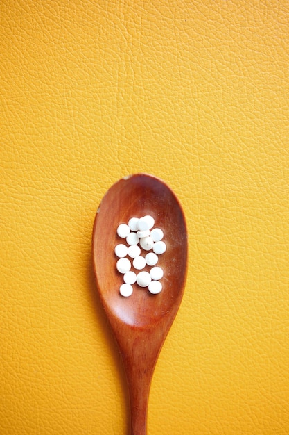 Artificial sweetener container on a spoon on orange background