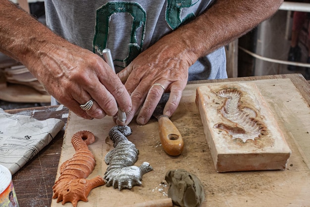 руки ремесленника делают морских коньков из глины