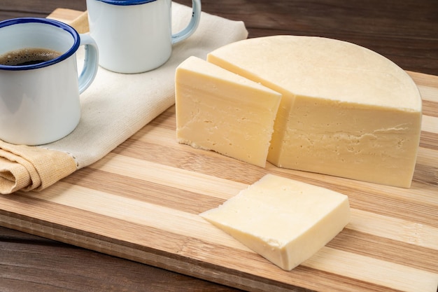 Artisanal Alagoa cheese from Minas Gerais Brazil over a wooden board with coffee