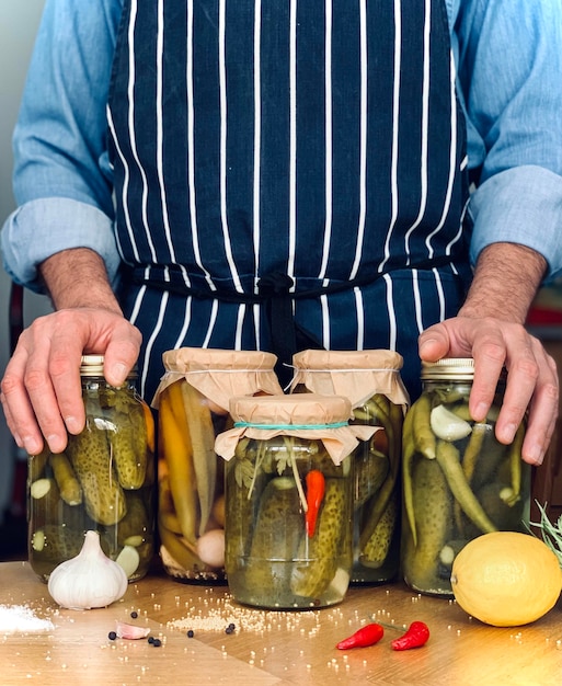 Photo artisanal a man in apron is doing pickles jars stock for winter season organic homemade pickles