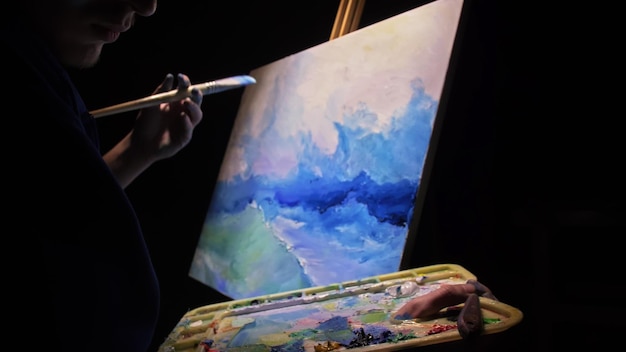 Художник-копиист рисует морской пейзаж с кораблем в океане Ремесленник-декоратор рисует, как лодка плывет по синему морю