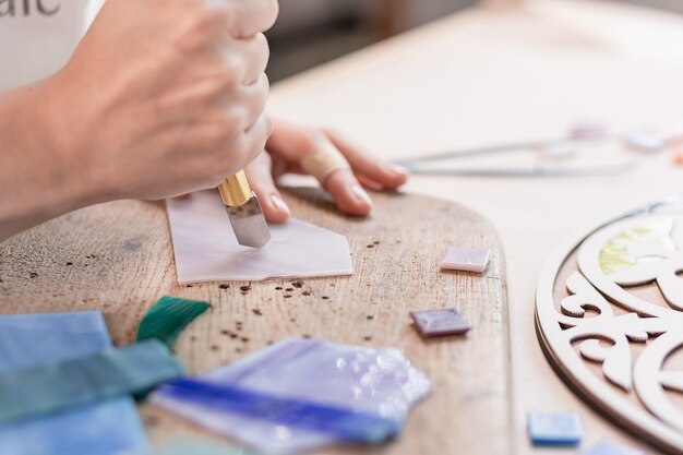 Artist cutting sheets of stained glass into small mosaic squares. Close-up