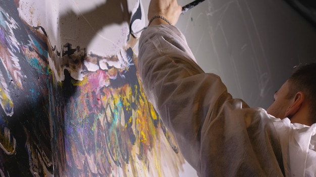 Artist designer draws an eagle on the wall Craftsman decorator paints a picture with acrylic oil color Painter painter dressed in a paint coat Indoor Dark magic cinematic look