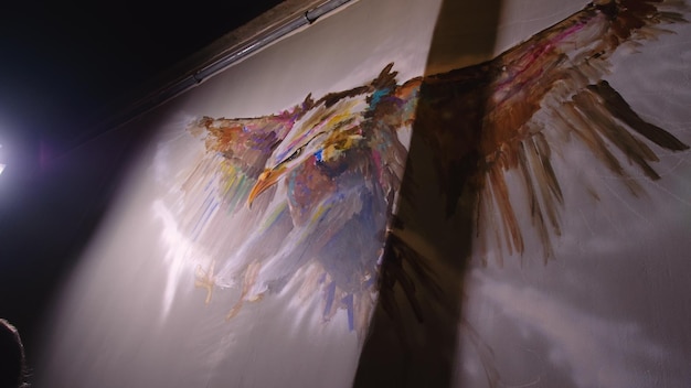 アーティストのデザイナーが壁にワシを描く職人のデコレータがアクリル油絵の具で絵を描く