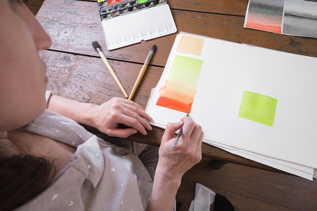 Artist draws colorful gradients in watercolor paint on a white canvas with an art brush