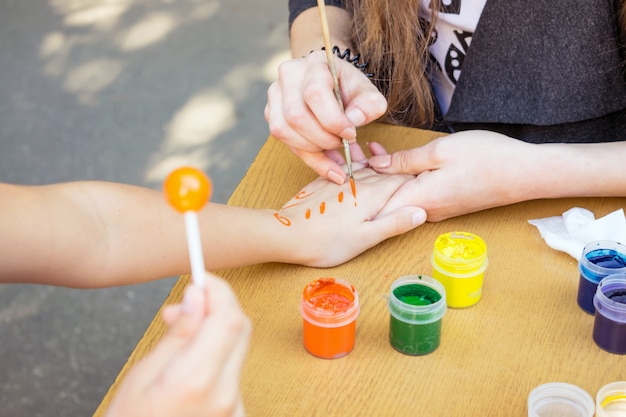 Artist draws a pattern on the child's hand