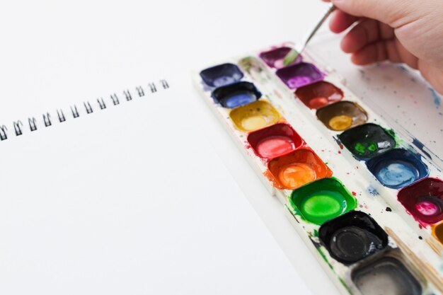 Artist hand with watercolor dye and notebook