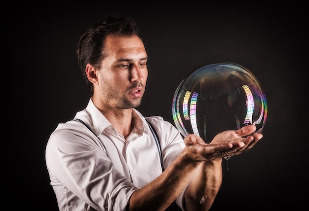 Artist hold big soap bubble in his hands bubble show studio
concept