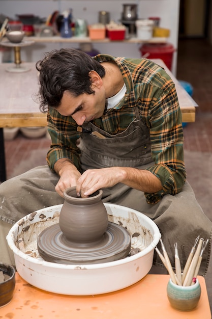 Artist makes clay pottery on a spin wheel in workshop