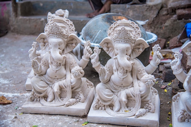 Artista che fa una statua e dà il tocco finale a un idolo del dio indù lord ganesha in un laboratorio di artisti per il festival di ganesha