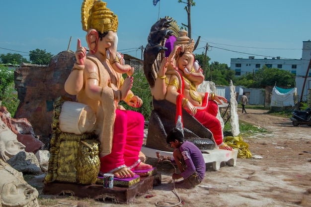 Foto artista che fa una statua e dà il tocco finale a un idolo del dio indù lord ganesha in un laboratorio di artisti per il festival di ganesha