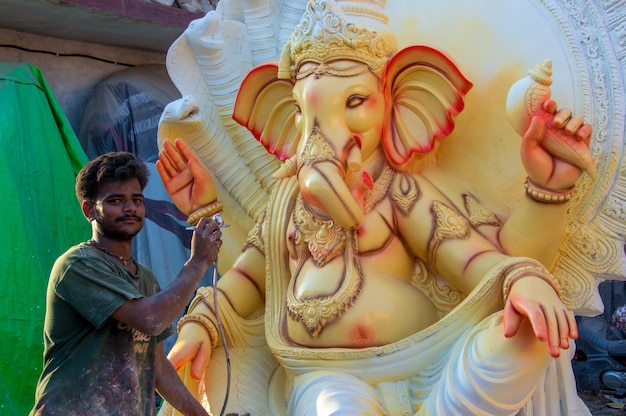 Artist making a statue and gives finishing touches on an idol\
of the hindu god lord ganesha at an artist39s workshop for ganesha\
festival