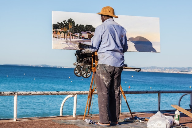 An artist paints in oil on the English coast in Nice, France