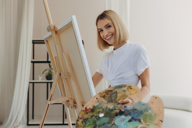 The artist paints in the studio Attractive girl wearing a white Tshirt