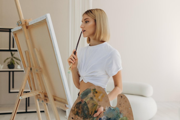 The artist paints in the studio Attractive girl wearing a white Tshirt