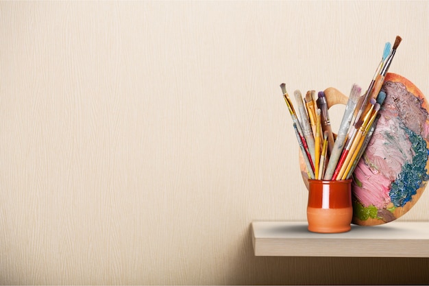 Artist palette, colors and brushes on the shelf